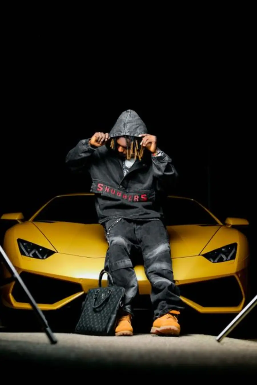 Stylish person in front of a sleek yellow sports car, casual urban vibe.