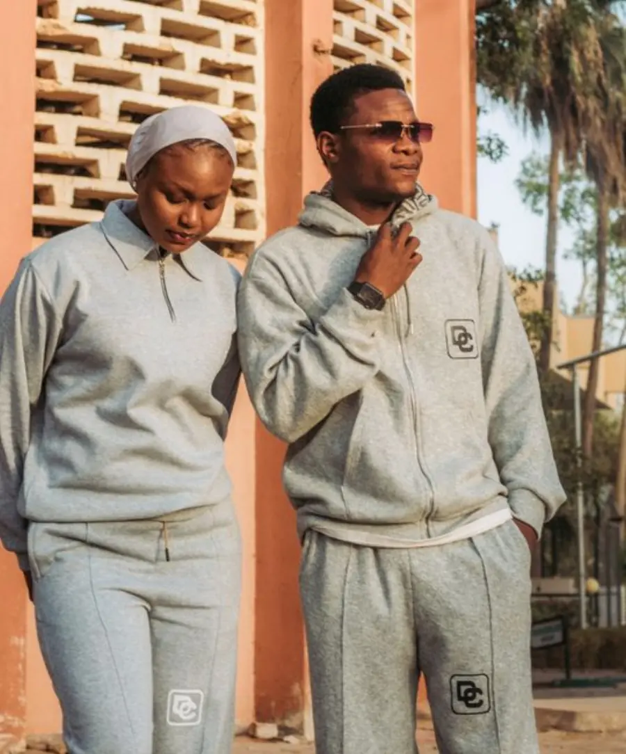 Two adults in matching grey casual outfits during a sunny outdoor photoshoot.